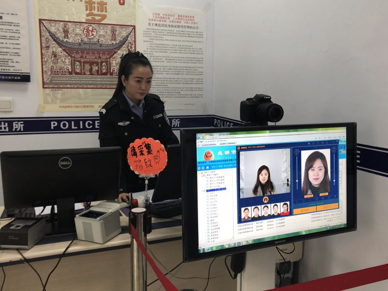 图六 户籍大厅中，民警向记者展示最新的证件照拍摄方式
