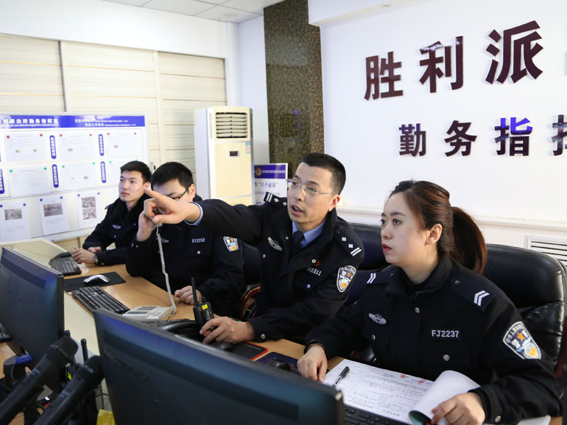 图二：李兵（右二）向记者（右一）介绍视频监控中辖区的情况