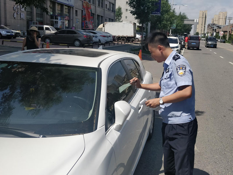 烈日下民警在违停车辆上贴警告通知单