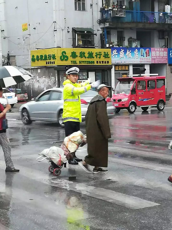 交警边指挥交通边帮助老人过马路