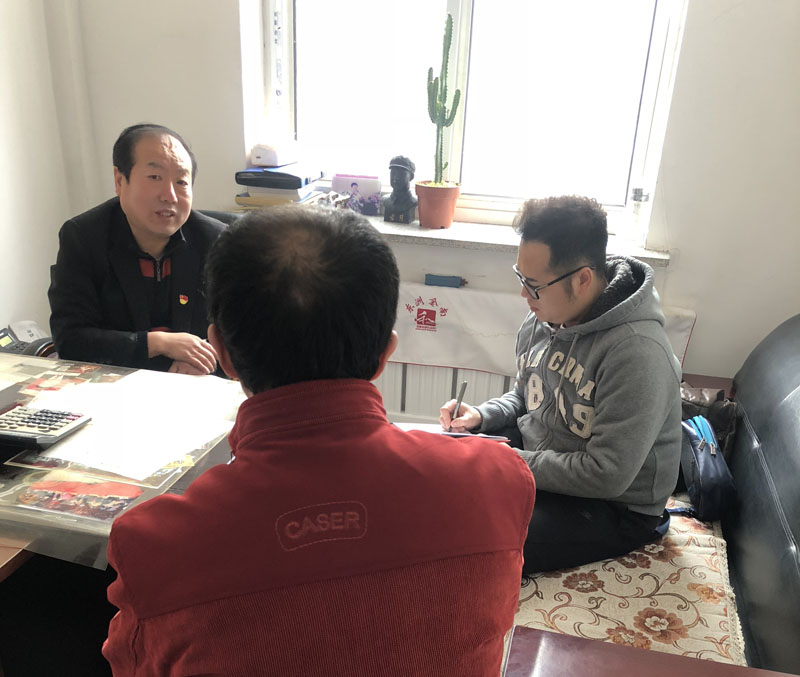 记者（右一）与马庆国（左一）一起与社区居民聊天