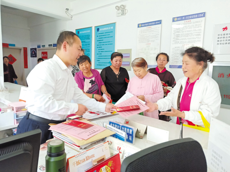 配文1：社区工作者向居民发放普法宣传册