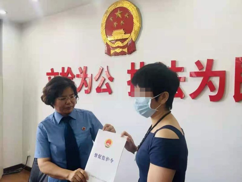 监护人（右）从检察官手中接过《督促监护令》