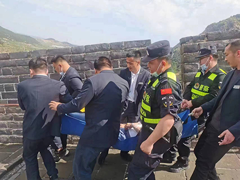 民警与景区工作人员将患病游客抬下长城。