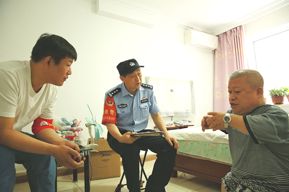临退休前，社区民警王忠利（左二）和网格员去刘学成家中走访
