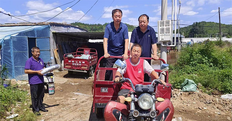 辽宁省食用菌协会副会长刘喜杰乘坐当地三轮车前往受灾现场