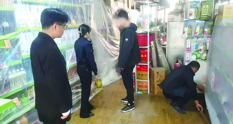 二图，法院干警正在帮助一楼商户粘贴防尘塑料布