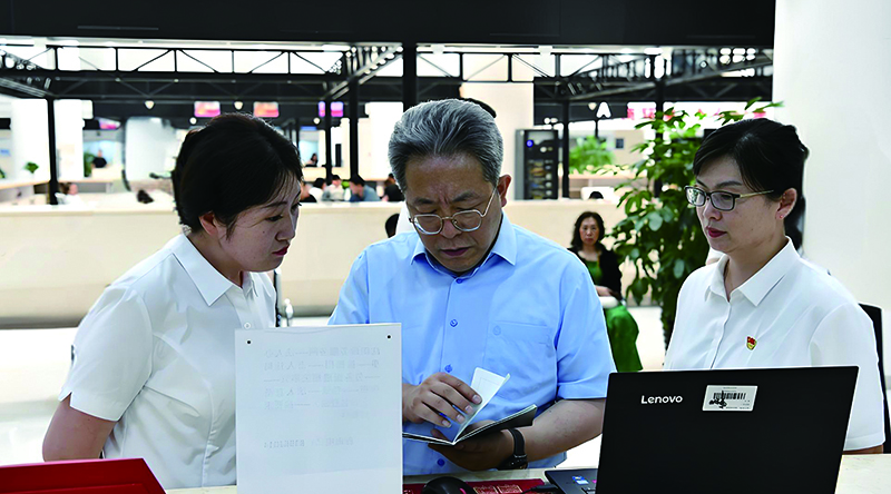 沈阳市司法局党组书记、局长张勇航（左二）在市政务服务中心向窗口工作人员了解审批流程