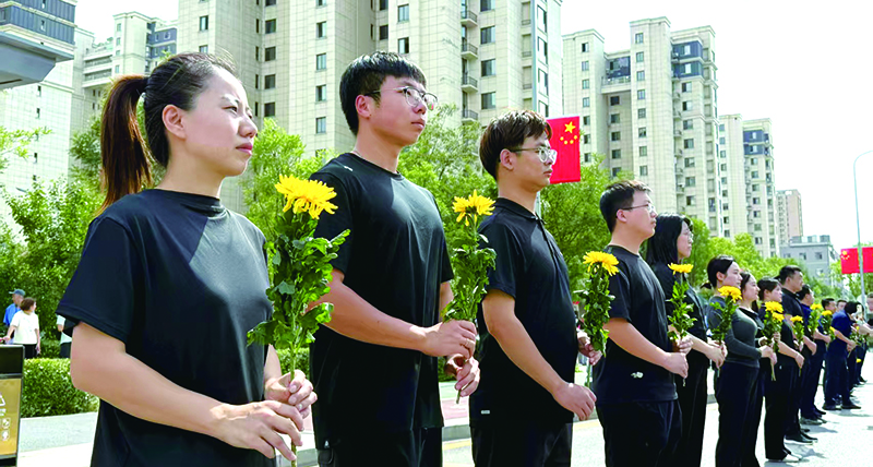 志愿者手持菊花以整齐队列迎接英雄回家
