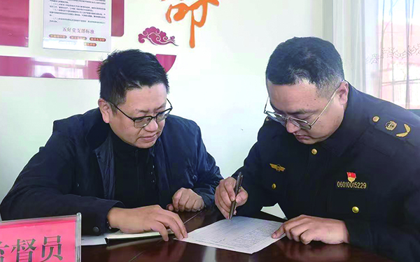 监督员王雨飞（左）现场监督执法队员于宁（右）填写《月度自查清单》