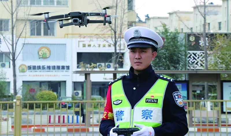 头题图，交警在执勤工作中准备使用“无人机”监控车流量。