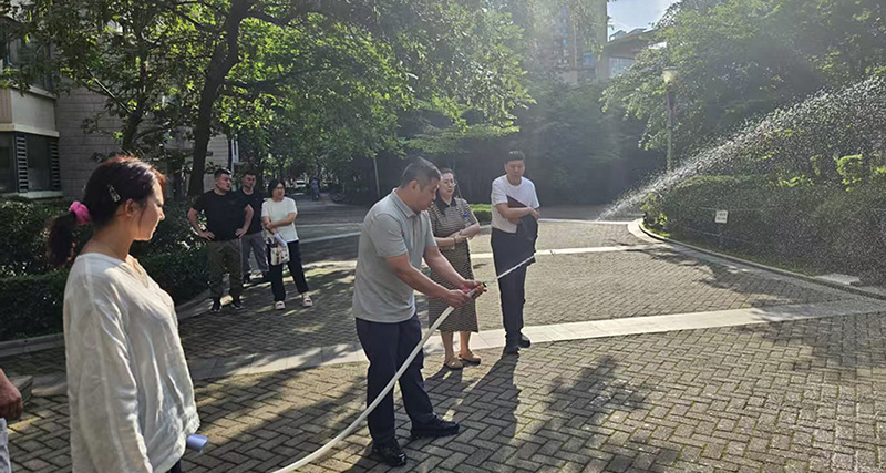 头题图，物业经理为居民演示轻便消防水龙的使用方法1